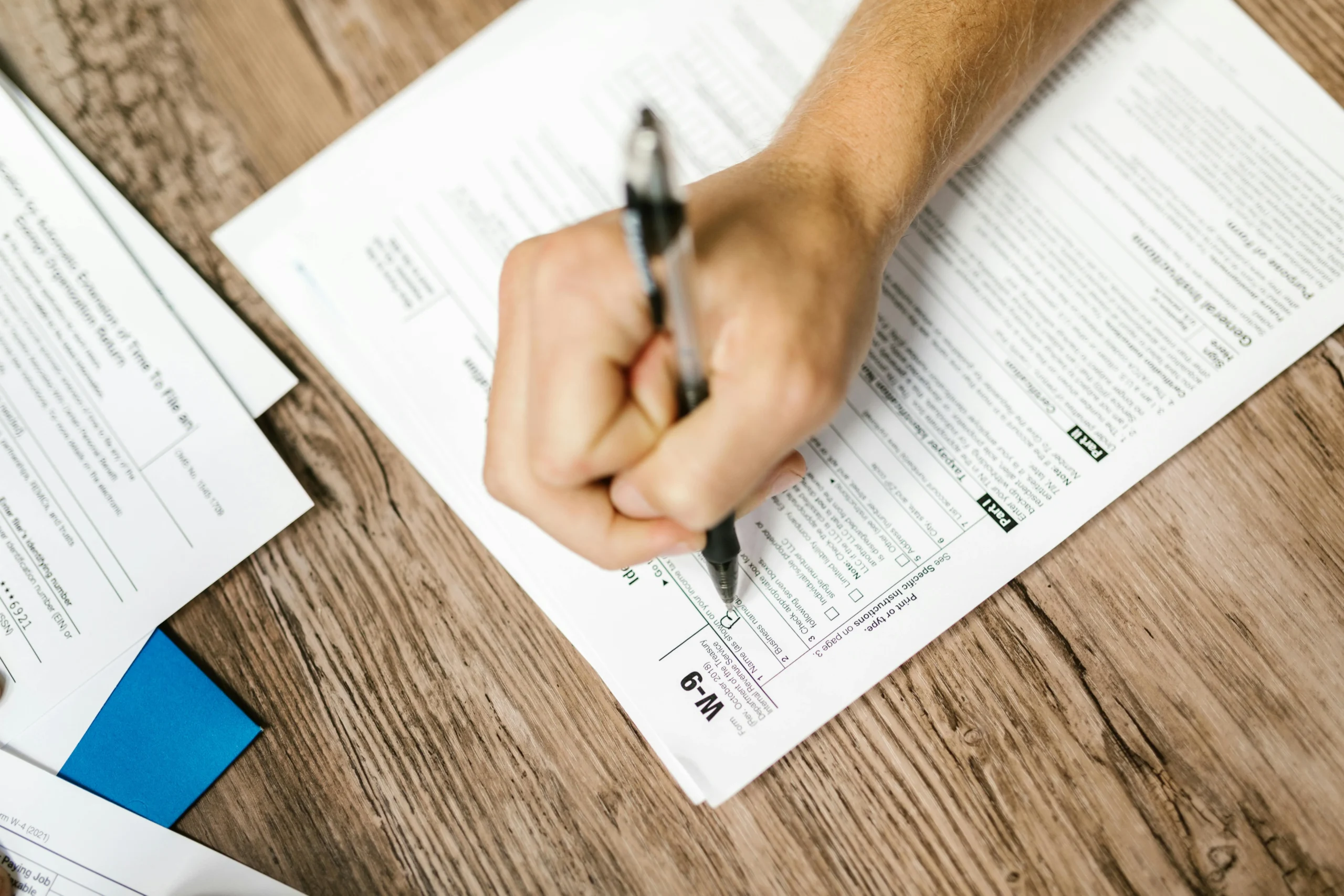 529 to Roth IRA rollover 2026: Ultimate Guide for Families 3 529 to Roth IRA rollover 2026: Hand writing on a W-9 tax form using a ballpoint pen on wooden desk