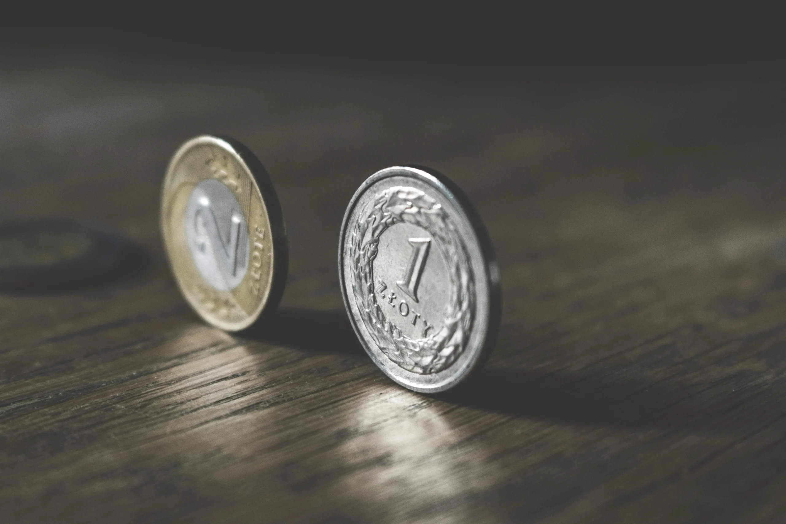 capital gains tax 2026: Close-up of Polish zloty coins standing on a wooden table, showcasing metal reflections