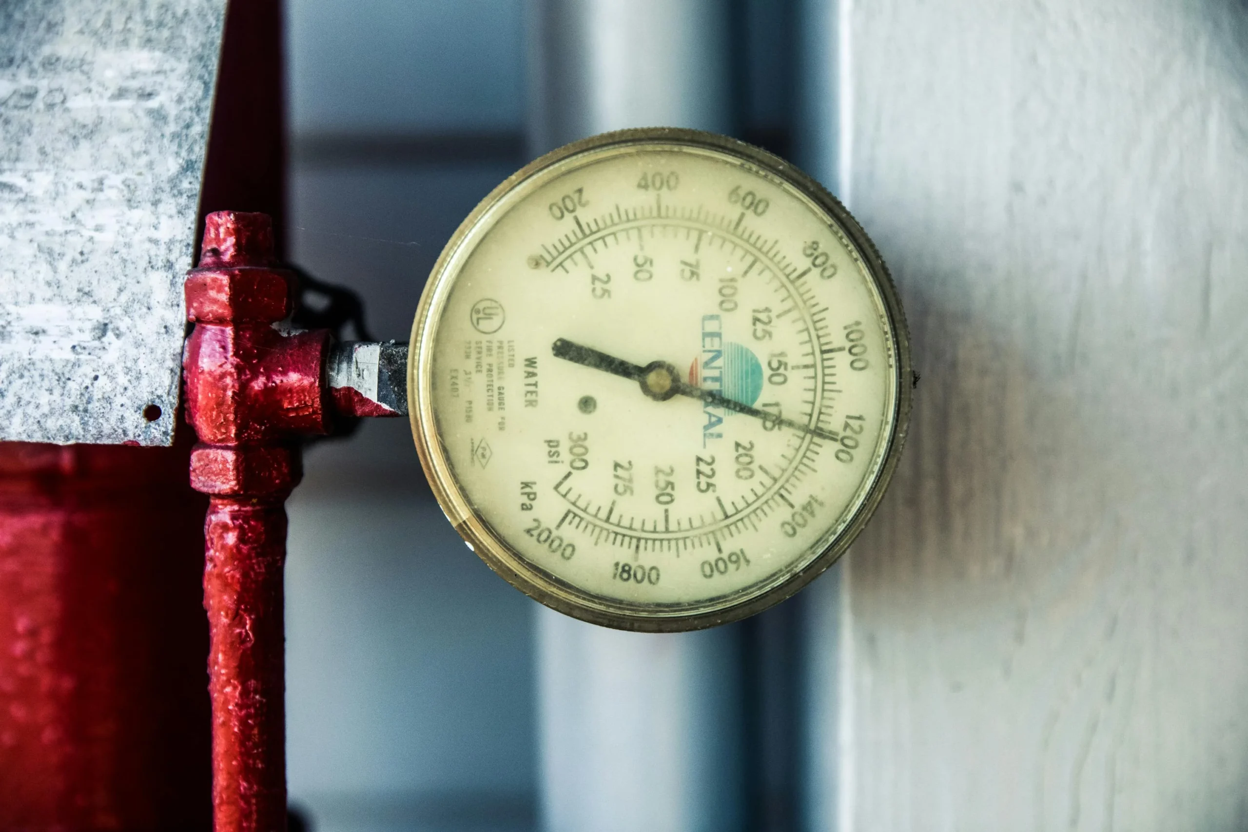 credit card utilization strategy 2026: Detailed view of a pressure gauge attached to a red industrial pipe, measuring PSI and