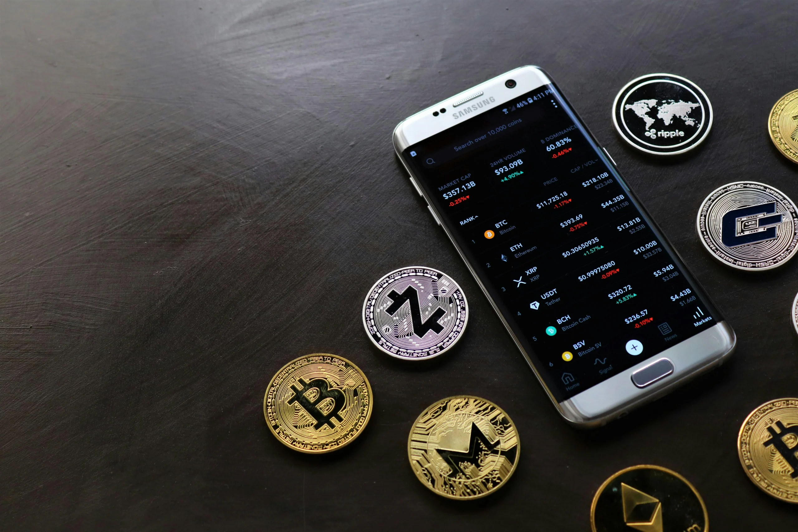 crypto bonus — A collection of cryptocurrency coins and a smartphone displaying a digital trading platform.