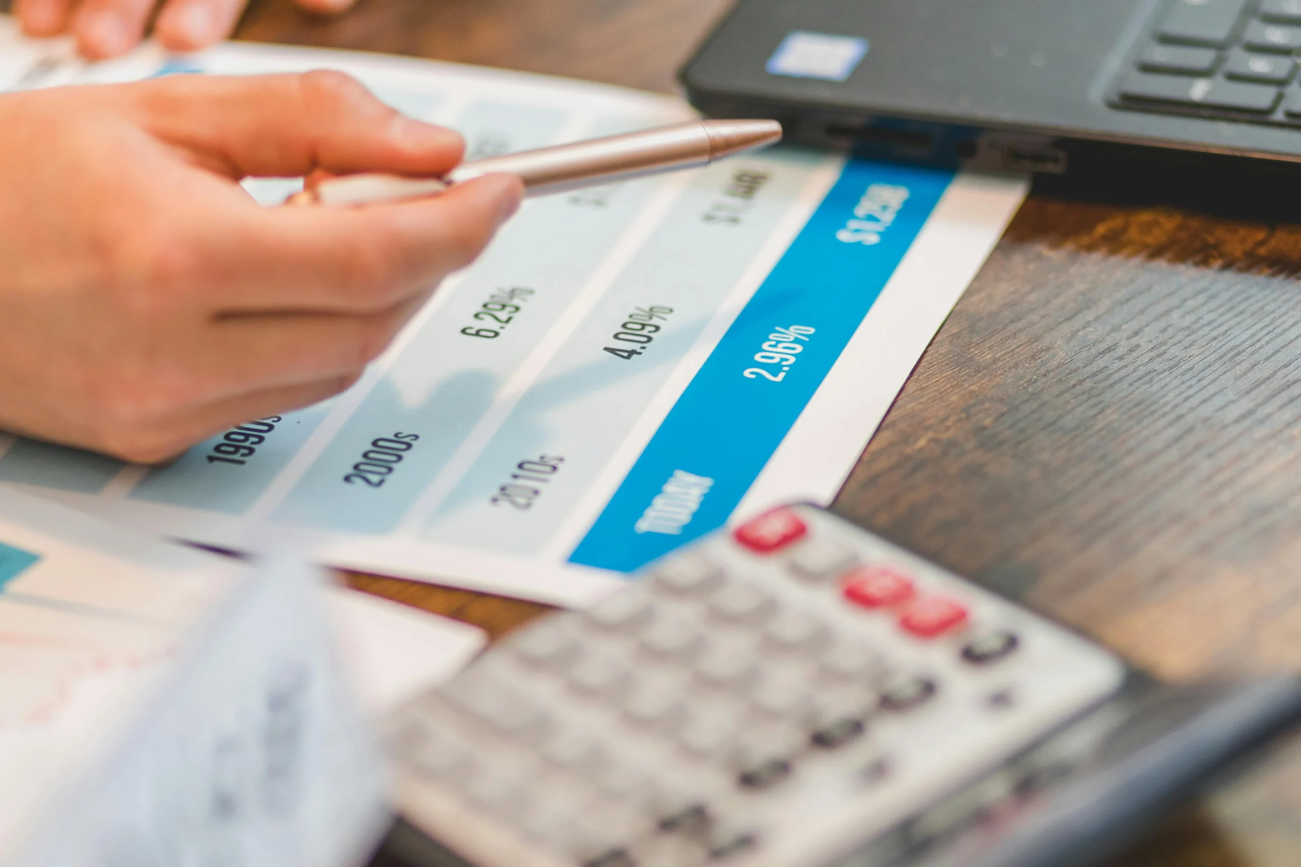 debt avalanche vs debt snowball 2026: Close-up of a hand using a ballpen and calculator to analyze interest rates on a chart