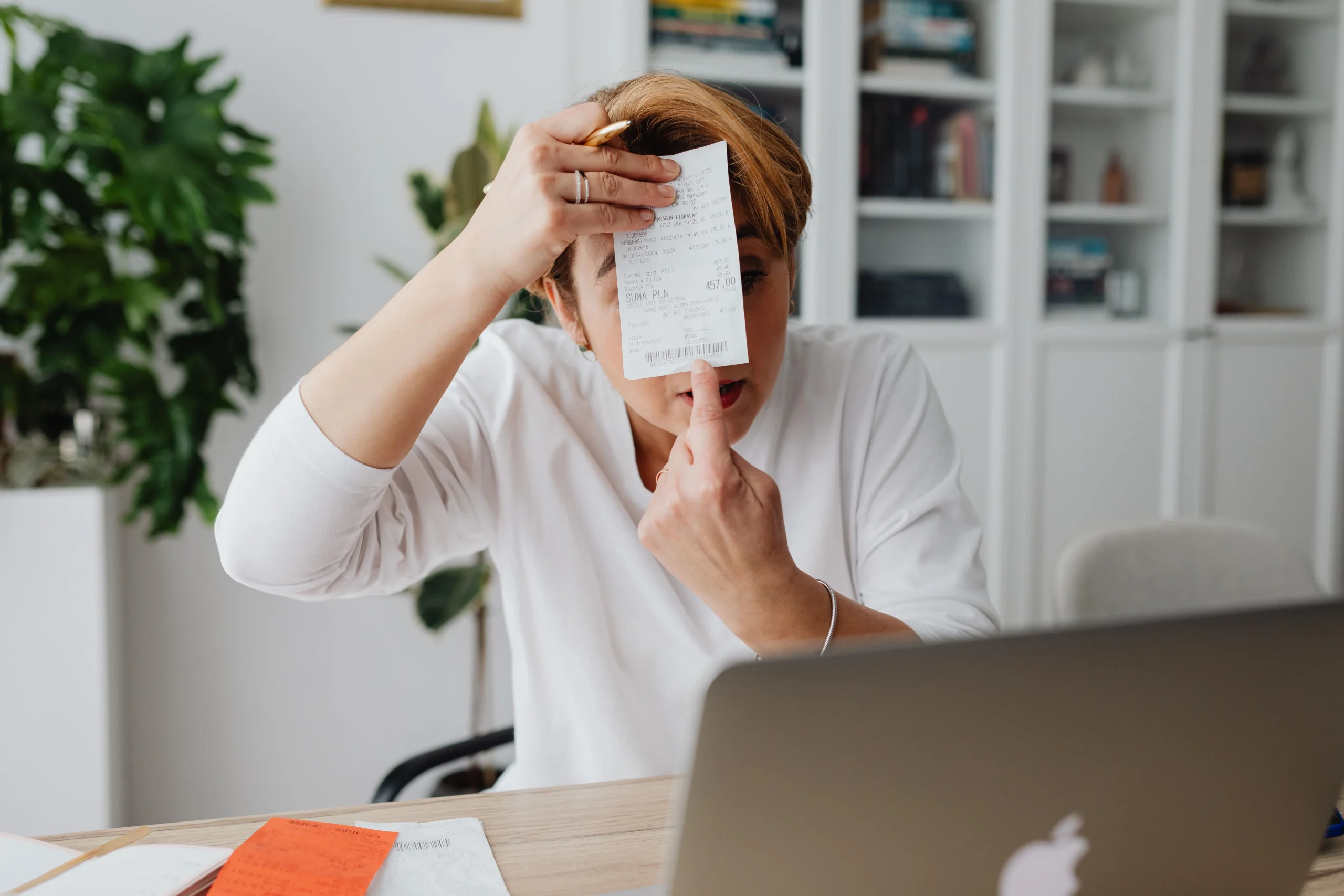 debt avalanche vs debt snowball 2026: Businesswoman showing a receipt during a home office work session, highlighting technol