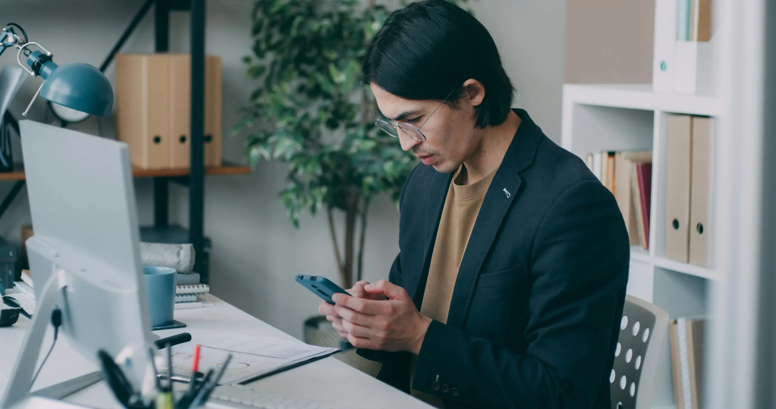 Disability Insurance High Earners 2026: 7 Essential Secrets 3 disability insurance high earners 2026: Young man in an office using smartphone while working at a computer desk
