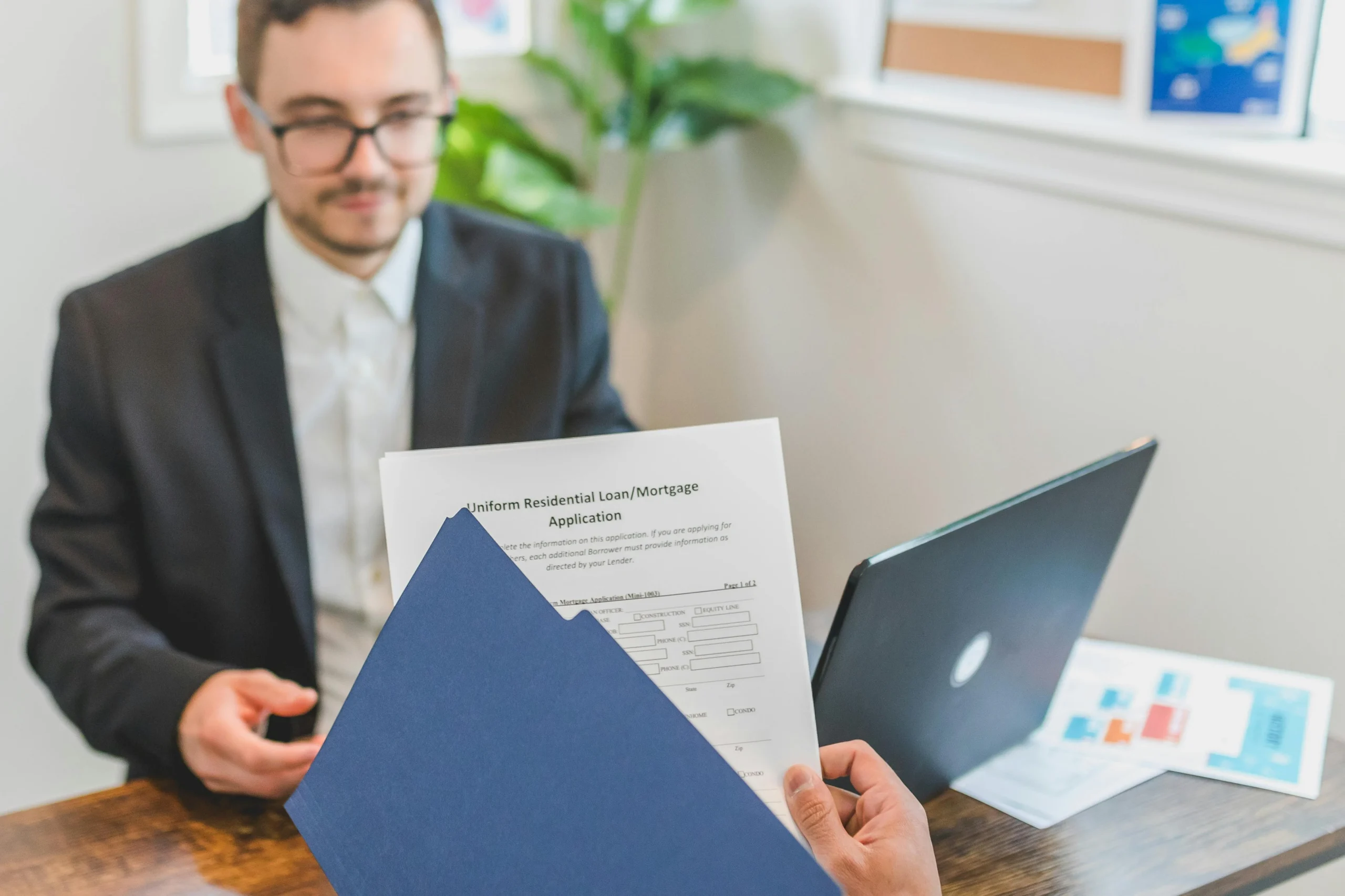 first time homebuyer programs 2026: Mortgage broker and client discussing loan application with documents on table