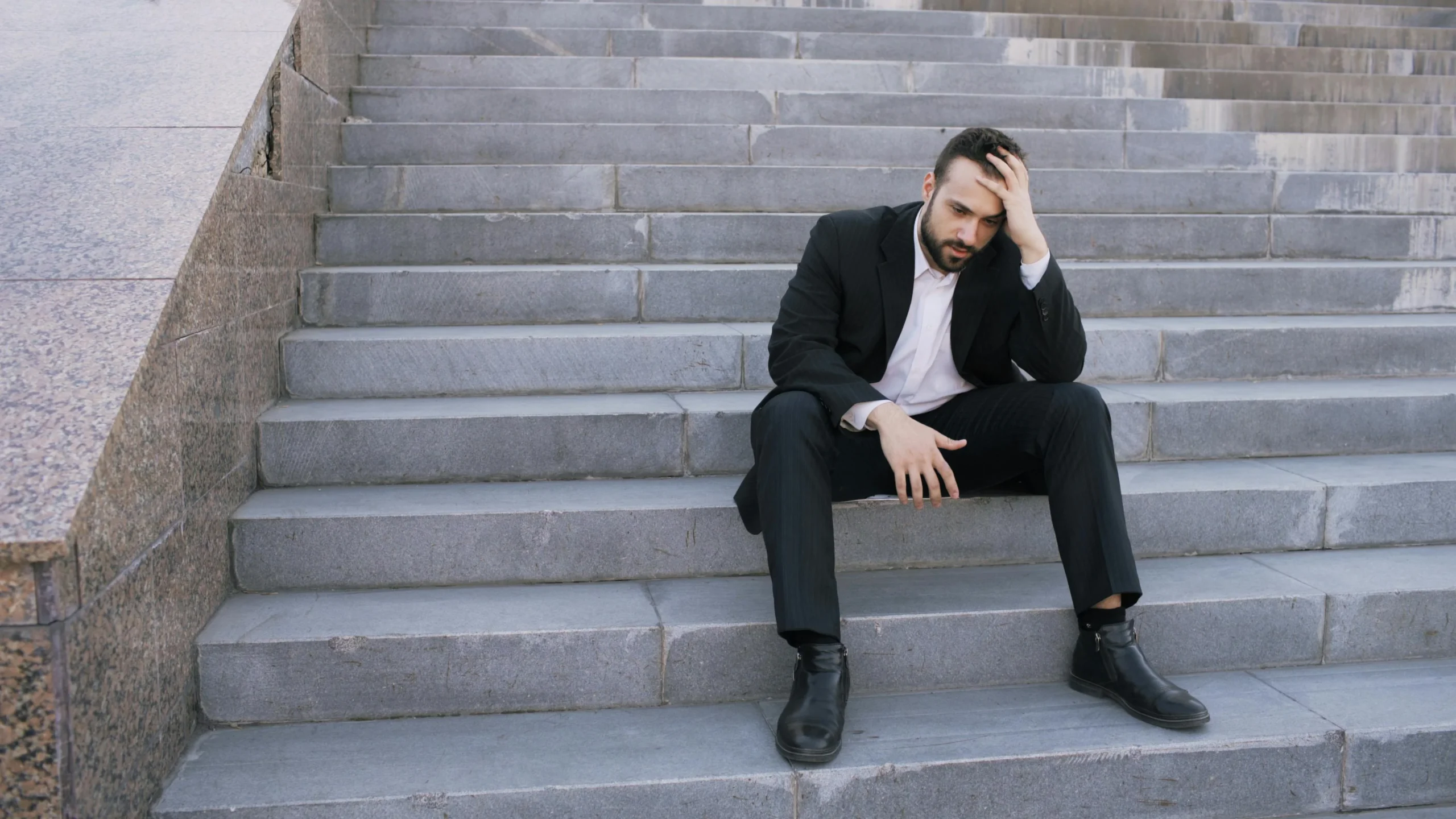 capital gains tax 2026: Businessman in a suit sitting distressed on concrete stairs, facing challenges
