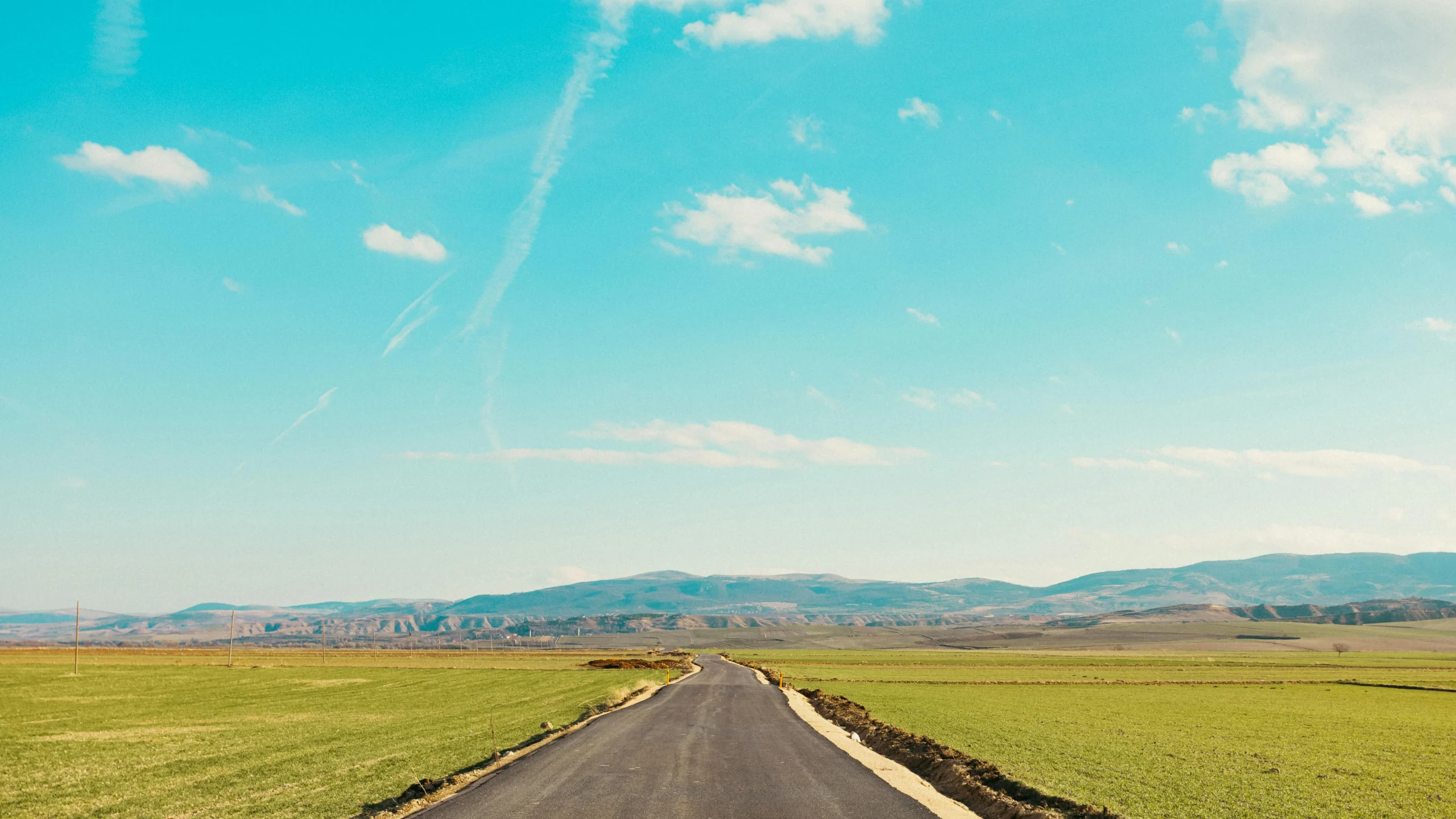IRA rollover rules 2026: A serene countryside view with a paved road leading towards distant mountains