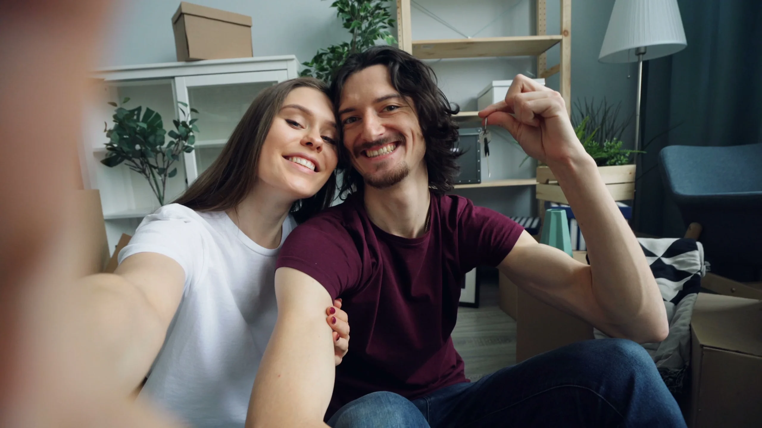 mortgage recast vs refinance 2026: Smiling couple taking a selfie while moving into their modern apartment, displaying the ex