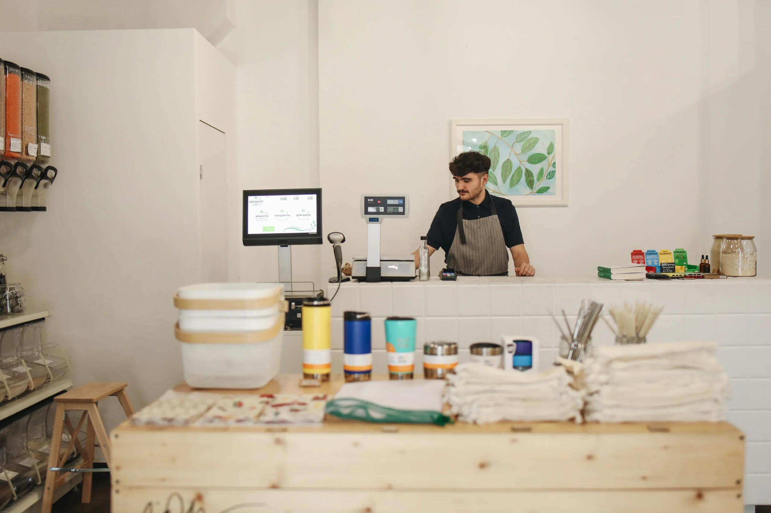 small business health insurance 2026: Young man managing a zero waste retail store, focused on ethical shopping and sustainab