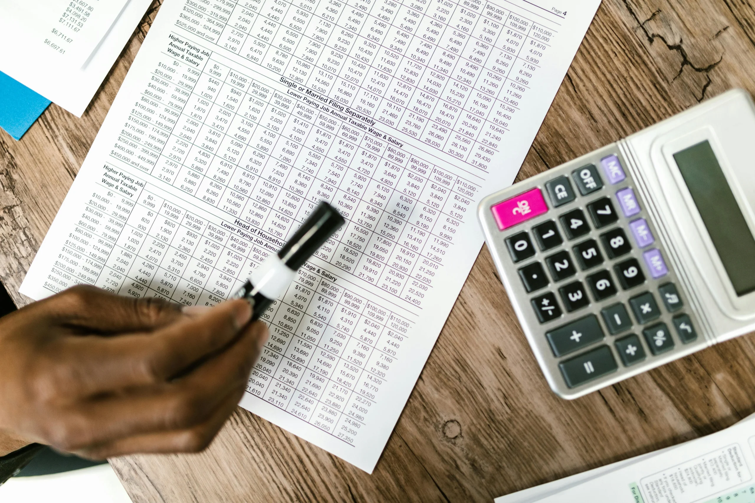 PSLF Buyback: Close-up of tax documents and calculator on wooden table, highlighting financial analysis