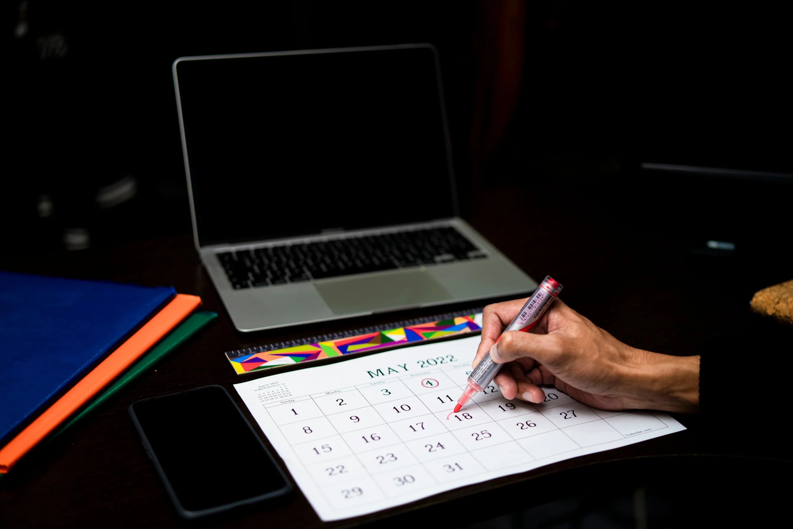 RMD Rules 2026: Ultimate Guide — Avoid Costly Penalties 2 RMD rules 2026: A person plans on a calendar at a desk with a laptop and phone, May 2022