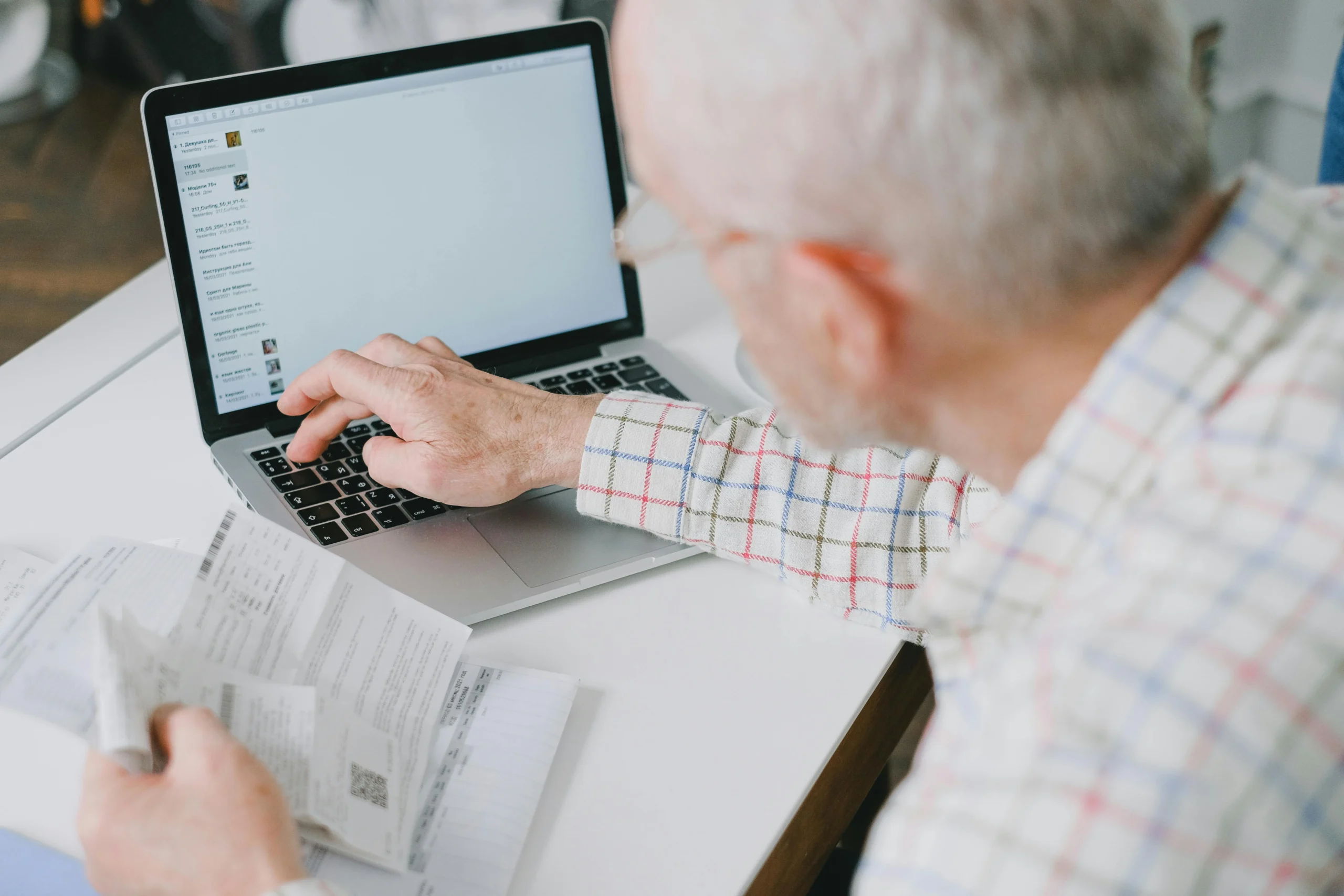 solo 401k vs SEP IRA 2026: Elderly man at desk handling finances online with documents and laptop