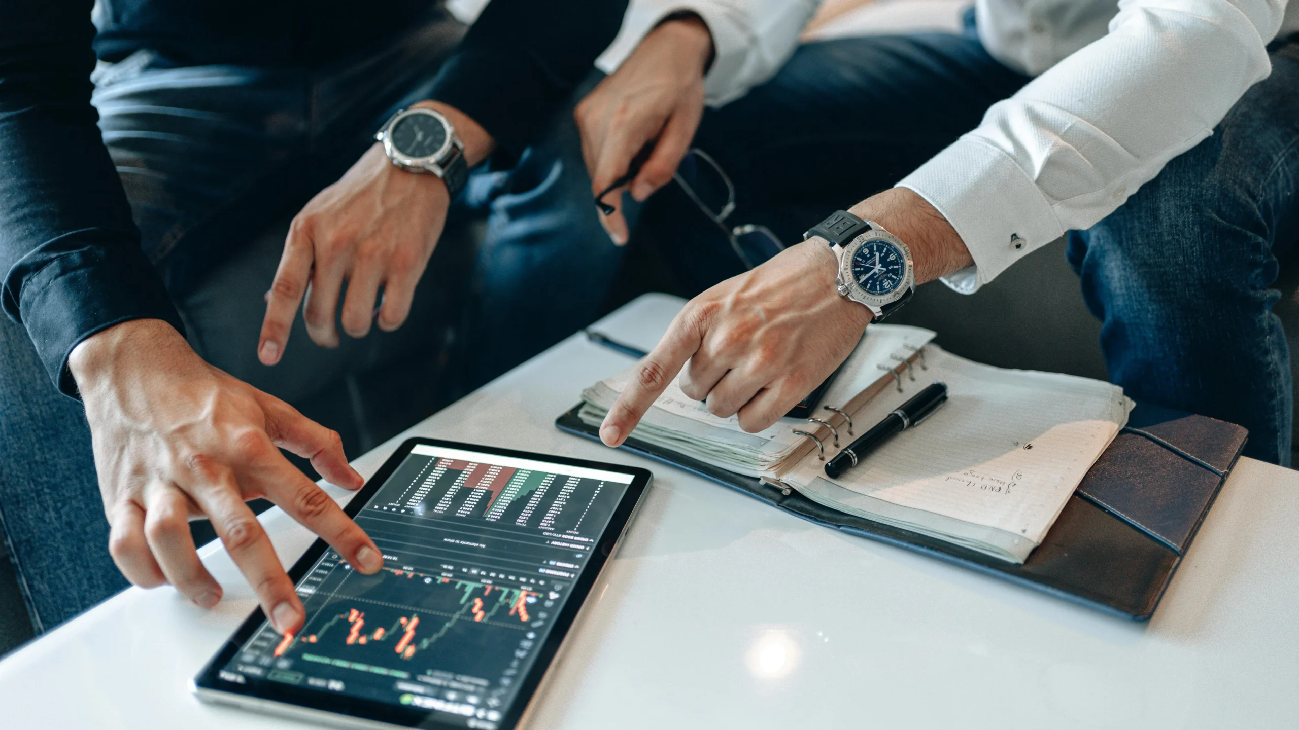 tax loss harvesting 2026: Two businessmen discussing financial data on a tablet during a meeting