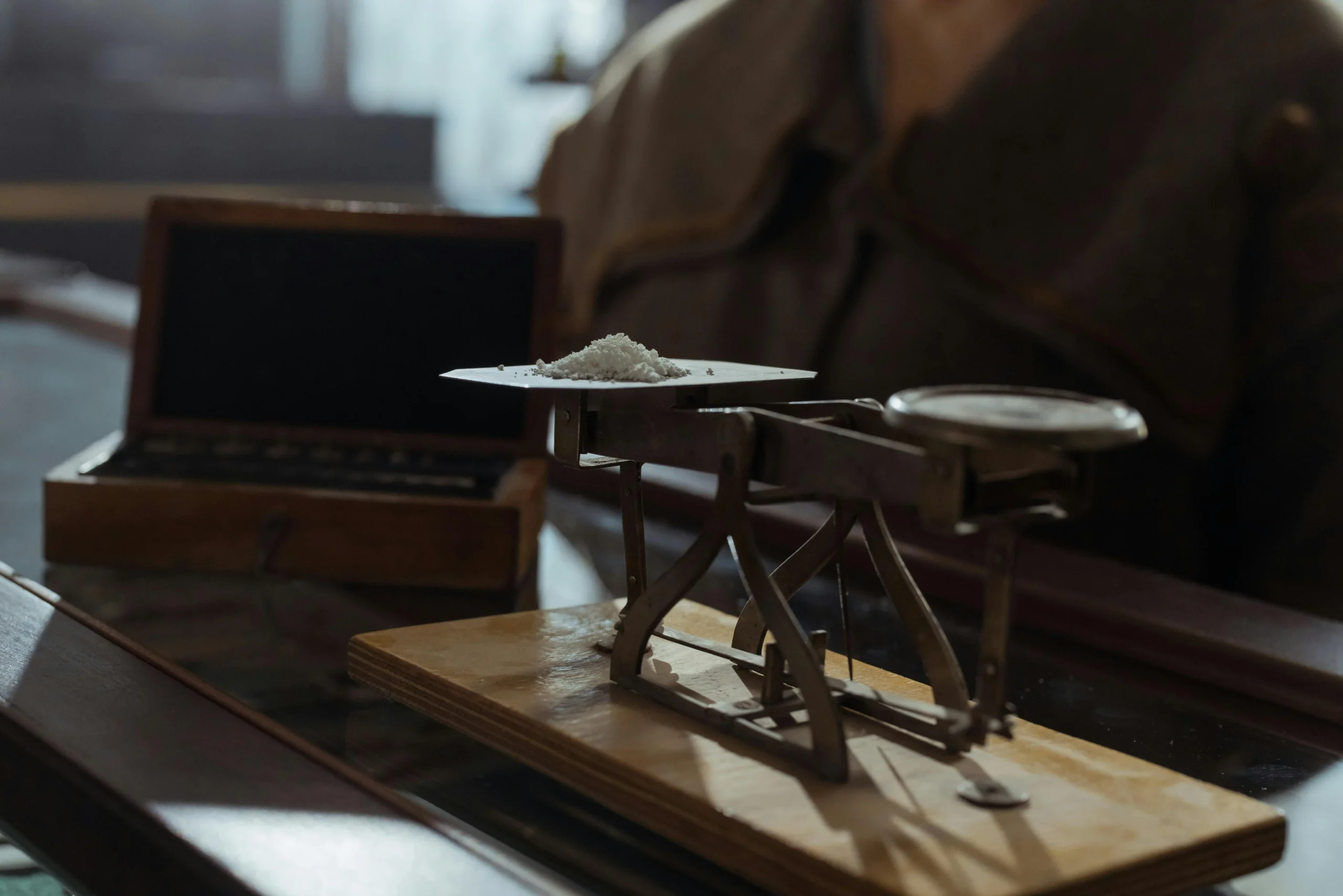 traditional vs Roth 401k 2026: Classic vintage weighing scale with a small heap of white powder placed indoors on a wooden su